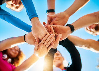 Wall Mural - Gather around. Low angle shot of a group of young cheerful friends forming a huddle before a fitness exercise outside during the day.