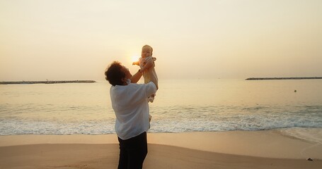 Wall Mural - happiness Asian family grandmother is keeping on her arms holding and playing with cute adorable newborn baby infant girl on a seaside beach at sunrise during holiday vacation in Thailand	
