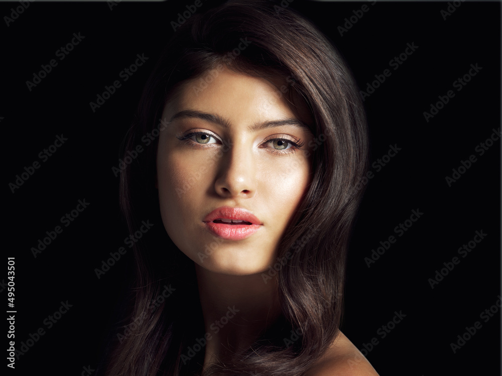 Captivating yet charming. Studio close up shot of a beautiful woman posing against a black background.