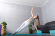 © somemeans - Young woman practices side plank asanas with yoga blocks. Pilates block yoga foam brick. Yoga at home.