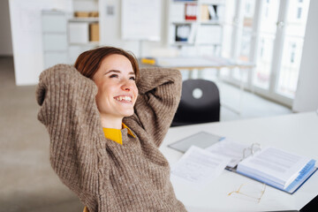 Wall Mural - young modern business woman sits at desk and looks up relaxed