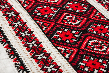 Fragment of Ukrainian national embroidery, handmade vyshyvanka shirt embroidered with red and black threads. National clothing of Ukraine. Close-up shot, selective focus