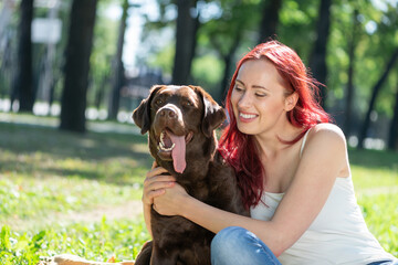 Poster - Young attractive woman hugs her dog in the park.