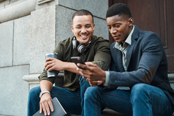 Poster - Work where motivates you to make things happen. Shot of two young businessmen using a smartphone together against an urban background.