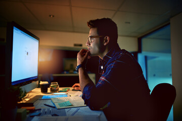 Sticker - He eats deadlines for dinner. Shot of a young businessman using a computer during a late night at work.