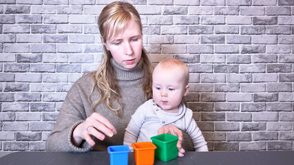 Wall Mural - Mother playing with little kid on gray brick wall background. Copy space for text