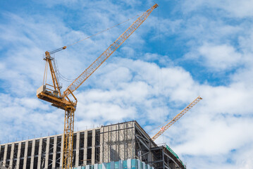 Modern building and tower crane in construction site with blue sky background. Construction industry concept
