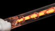 © KPixMining - Glowing coiled resistance wire inside heating element on a black background. Closeup of orange hot metal conductor in vacuum glass tube. Conversion electric energy into heat in laser printer finisher.