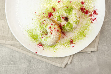 Vegan donuts topped with healthy white glaze with coconut flakes and desiccated coconut on plate on gray background.