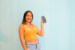 Retrato de una chica bastante alegre y alegre cogida de la mano usando celular que muestra un anuncio  aislado sobre un fondo de color gris