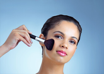 Aufkleber - With great skin comes a great makeup routine. Studio portrait of an attractive young woman applying makeup with a brush against a blue background.
