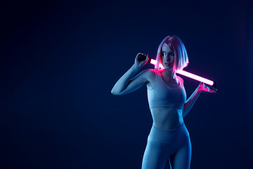 Woman in futuristic costume. Female in modern VR glasses interacting with network while having virtual reality experience. Augmented reality game, future technology, AI concept. VR. Neon violet light.