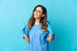 © luismolinero - Woman dentist holding tools over isolated on blue background giving a thumbs up gesture