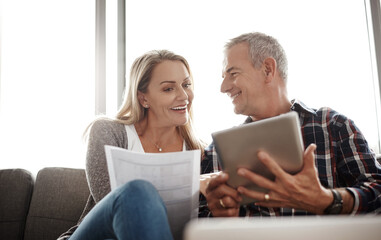 Poster - Couples who save together go on vacation together. Shot of a mature couple using a digital tablet while going through their paperwork together on the sofa at home.