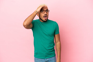 Poster - Young Colombian handsome man isolated on pink background doing surprise gesture while looking to the side