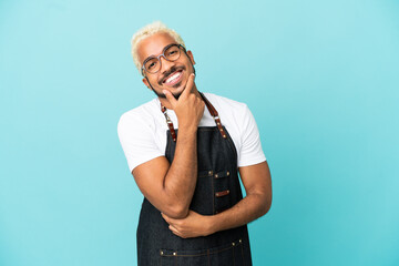 Wall Mural - Restaurant Colombian waiter man isolated on blue background smiling