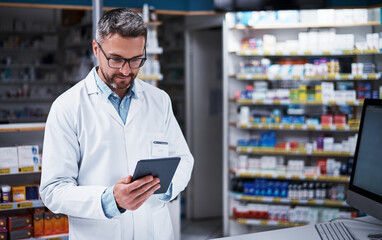 Aufkleber - Always informed, just what you want from your pharmacist. Shot of a handsome mature pharmacist using a digital tablet in a pharmacy.