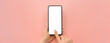 © Celt Studio - Hand holding cellphone device and touching screen on pink background. Isolated hands and smartphone on pink background. Female hand holding modern black cell phone in vertical position