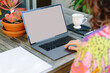 © Austockphoto - horizontal pic of a person using a laptop on a table with white tea cup and plants on a pot