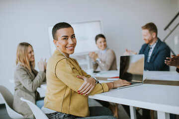 Young short hair business woman sitting in office and using laptop with her team