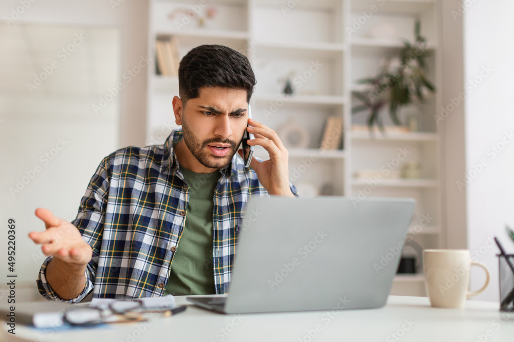Angry Arab man talking on cell phone using laptop Stock Photo | Adobe Stock