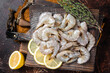 Raw tiger white shrimp prawn on board with herbs. Dark background. Top view