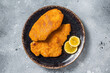 Roasted breaded german weiner schnitzel on a plate. Gray background. Top view