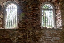 Old Arched Windows In An Abandoned Church, Iron Grilles In Front Of The Windows, Crumbling Window Sills And Window Sills
