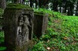 Remains of two ancient gravestones outgrowing with moss, one of them with religious sculpture, located on Island Of Art in center of Orava River Dam, northern Slovakia, Namestovo district.
