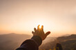 © Kittiphan - Young man hand reaching for the mountains during sunset and beautiful landscape