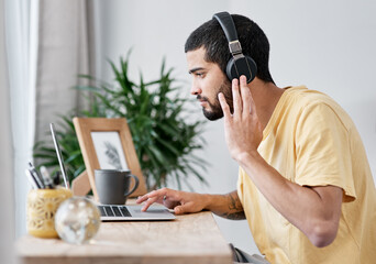 Poster - The best noise cancelling headphones in the business. Shot of a young man using a laptop and headphones while working from home.