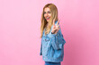 © luismolinero - Young Uruguayan blonde woman over isolated pink background smiling and showing victory sign