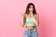 © luismolinero - Young caucasian woman isolated on pink background pointing to the side and doing silence gesture