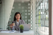 © Natee Meepian - Charming asian businesswoman sitting working on laptop in office.