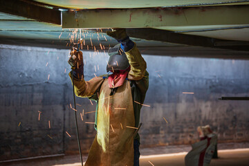 Welding male worker metal is part of machinery plate roof tank beam construction flash spark.