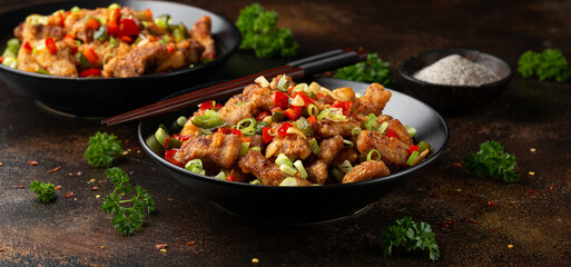 Wall Mural - Stir fry salt and pepper pork loin with herbs in black bowl. Asian food