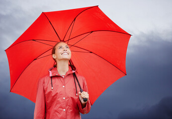 Im protected from the weather. A beautiful young woman standing outside with her red umbrella.