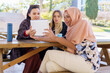 © javiindy - Cheerful diverse women sharing tablet during coffee break in cafe