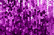 Background of fabric with sequins. A close-up shot of a shiny texture made of purple sequins