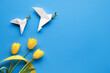 Dove of peace, paper origami. Peace to Ukraine. Yellow tulips, flowers, on blue background. Copy-space, place for text. Top view, flat lay, concept background.