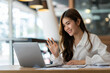 © crizzystudio - Happy young asian business woman waving hands to greeting partner during making video conference with her team.
