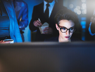 Poster - I work well under pressure. Cropped shot of a young woman working late with colleagues standing in the background.