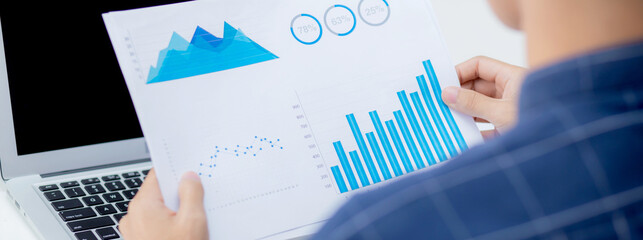 Hand of young business man looking document data graph and chart paper, marketing and investment, report of statistics profit for financial, economic and growth of finance, management and planning.