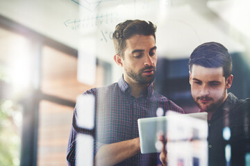 Aufkleber - Working on their top ideas to expand their company. Shot of two young businessmen using a digital tablet while brainstorming on a glass wall in an office.