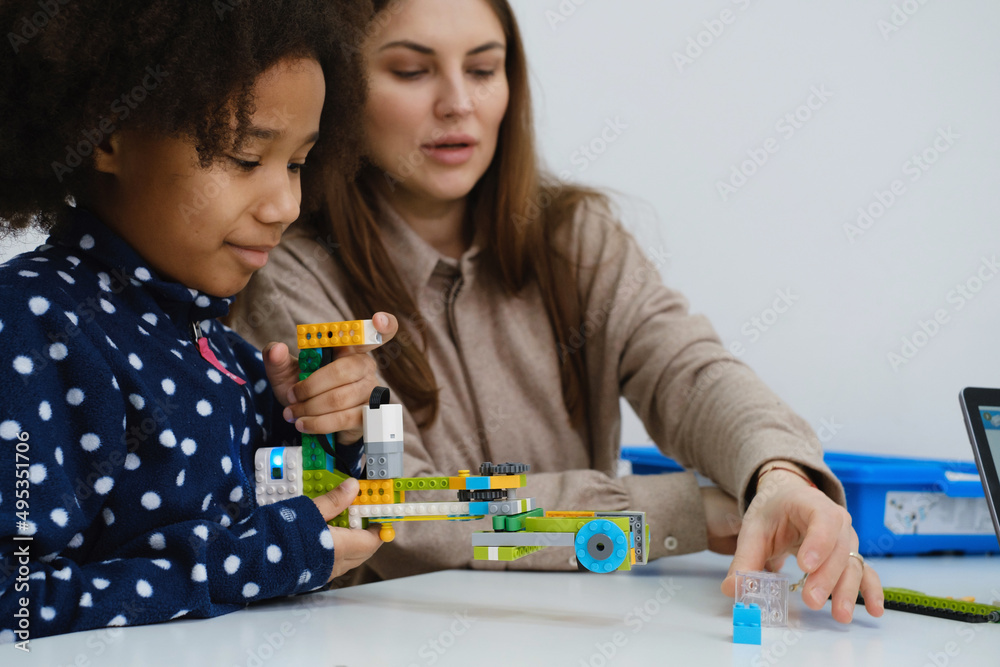 Multiethnic kids at STEM lesson constructing robot in classroom with ...