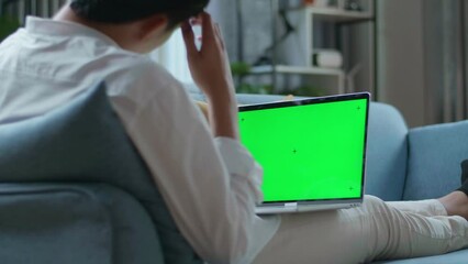 Man Being Tired While Lying On Sofa And Using Green Screen Laptop In The Living Room 

