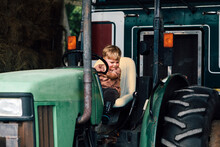 Happy Boy Sitting On Tractor In Farm