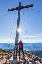 Female Hiker Standing Beside Summit Cross On Benediktenwand