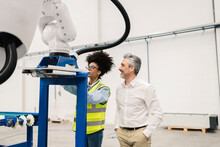 Engineer Analyzing Robotic Arm Machine Standing By Businessman In Factory