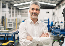 Smiling Businessman Standing With Arms Crossed In Factory